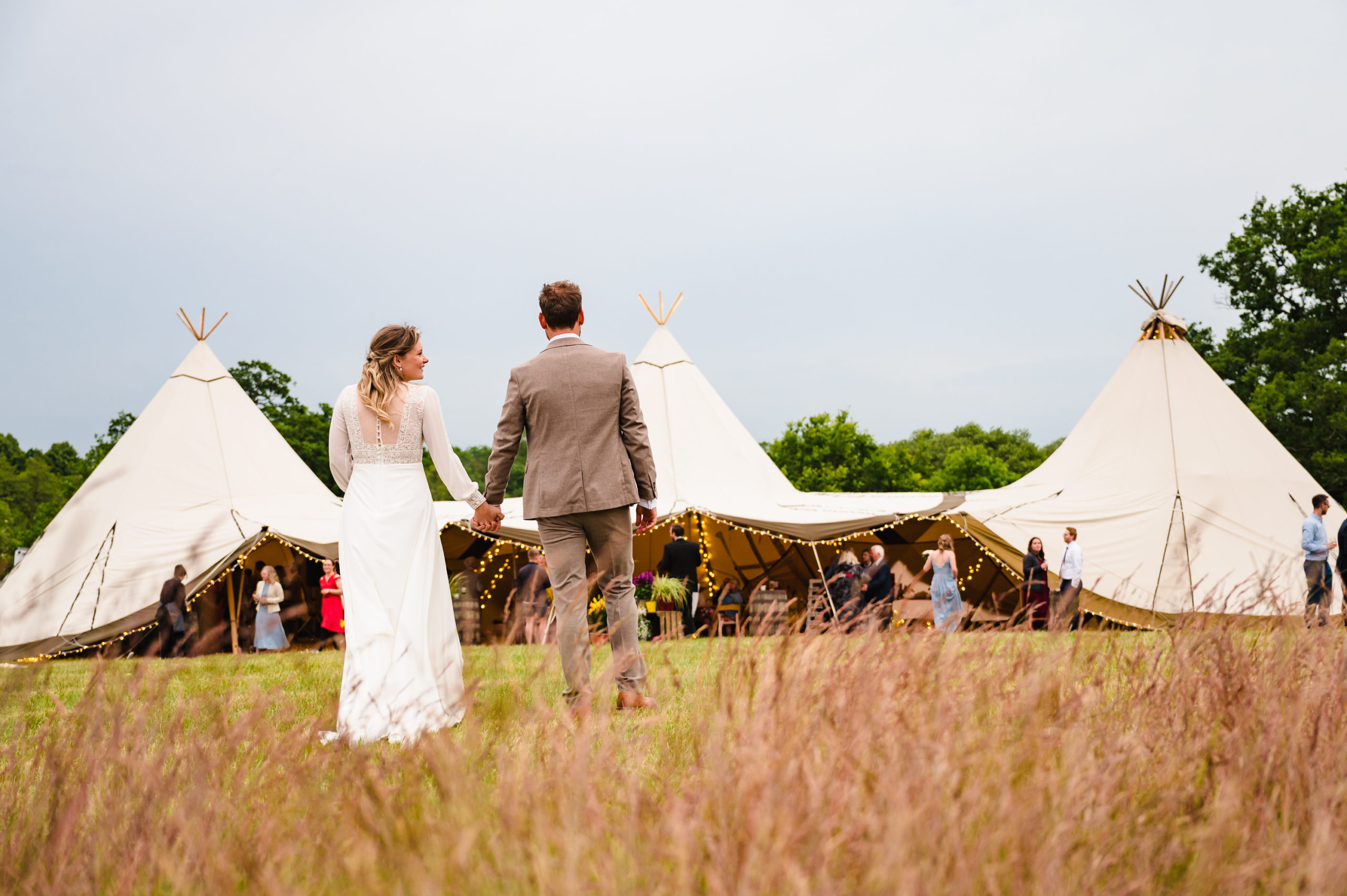 bride and groom walking towards their tipi