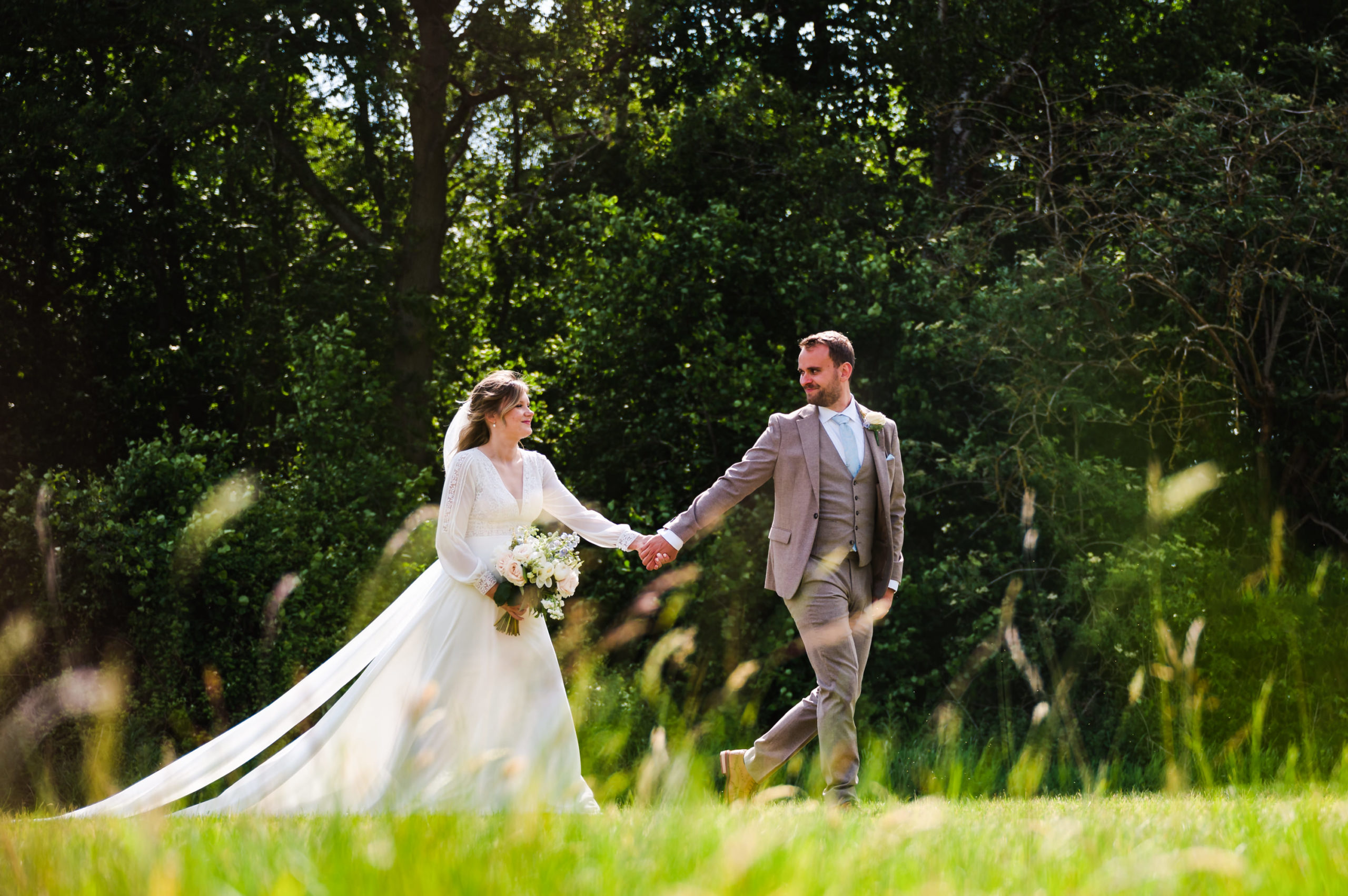 Bride and groom walking through a field